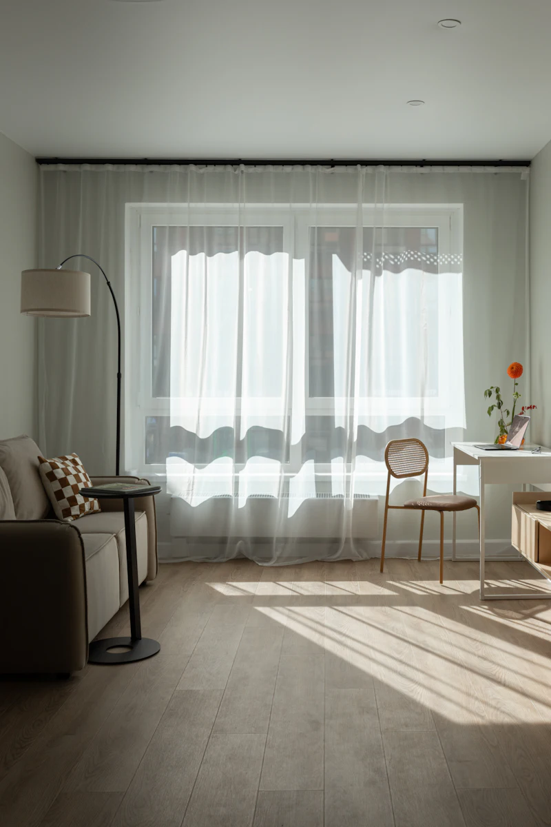 Sala de estar iluminada por cortinas leves e translúcidas